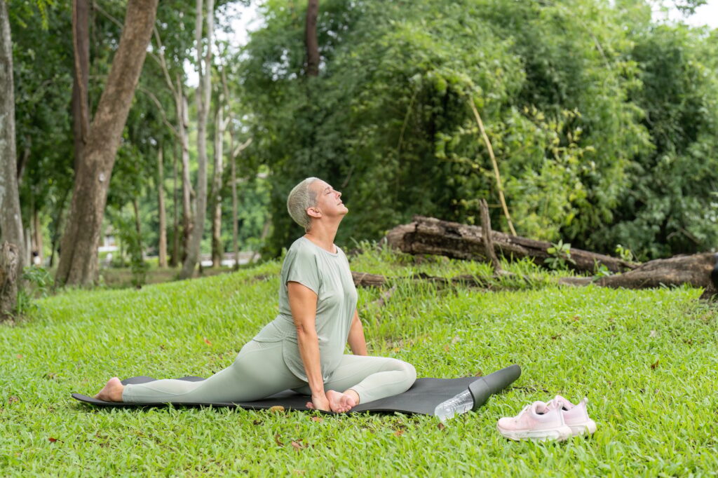 Elderly Woman Practicing Yoga Outdoors in a Lush Green Garden for Health and Wellness